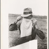 Farmer adjusting mask to avoid dust in haying operations. Lake Dick Project, Arkansas