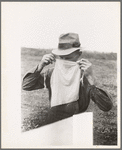 Farmer adjusting mask to avoid dust in haying operations. Lake Dick Project, Arkansas