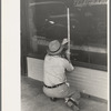 Window sign painter preparing to apply letters, Crowley, Louisiana