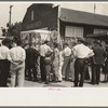 Groups of people standing in front of weighing concession with owner trying to drum up trade, state fair, Donaldsonville, Louisiana