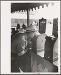 Man looking through penny peep show, state fair, Donaldsonville, Louisiana