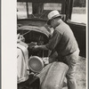 Junkyard owner working on automobile of farmer near Abbeville, Louisiana