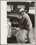 Junkyard owner working on automobile of farmer near Abbeville, Louisiana