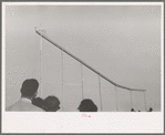 Crowd watch daredevil preparing to dive into water from cycle down elevated incline, state fair, Donaldsonville, Louisiana