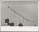 Crowd watch daredevil preparing to dive into water from cycle down elevated incline, state fair, Donaldsonville, Louisiana