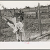 Daughter of Cajun cane farmer removing clothes from line near New Iberia, Louisiana