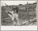 Daughter of Cajun cane farmer removing clothes from line near New Iberia, Louisiana