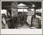 Owner atop his turpentine still. Goosneck runs from the still to the condenser coils where vapors are chilled. State Line, Mississippi