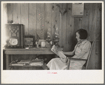 House wife reading in living room, Chicot Farms, Arkansas