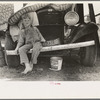 Son of white migrant sitting on bumper of their truck, Weslaco, Texas. Notice New Mexico license