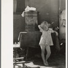 Child of migrant family in front of household goods of trailer home, Weslaco, Texas