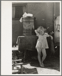 Child of migrant family in front of household goods of trailer home, Weslaco, Texas