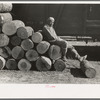 Negro resting on pile of logs to be loaded into box car, Eudora, Arkansas. These logs will be shipped to Tallulah, Louisiana to be made into barrel staves