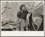 Child of migrant worker sitting on bed in tent home of cotton picking sacks, Harlingen, Texas