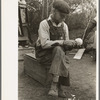 White migrant worker sawing wood for stakes to be used in setting up tent home, near Harlingen, Texas