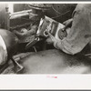 Migrant worker pouring oil into motor of automobile near Harlingen, Texas