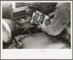 Migrant worker pouring oil into motor of automobile near Harlingen, Texas