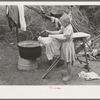 Child of white migrant worker ironing in camp near Harlingen, Texas