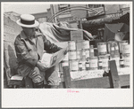 Honey peddler reading newspaper in market, San Antonio, Texas