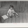 Mexican child on porch of house facing corral, San Antonio, Texas