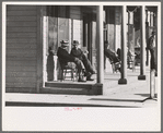 Men sitting in front of hotel in the early morning, Little Fork [i.e. Littlefork], Minnesota