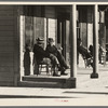 Men sitting in front of hotel in the early morning, Little Fork [i.e. Littlefork], Minnesota