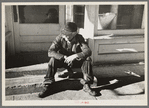 Arnegard, McKenzie County, North Dakota. Old man sitting on a store step