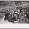 White migrant worker sitting in front of fire. He lived with two other white men migrant workers. He was a Texan. Harlingen, Texas