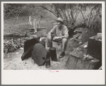 White migrant worker sitting in front of fire. He lived with two other white men migrant workers. He was a Texan. Harlingen, Texas