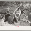 White migrant worker sitting in front of fire. He lived with two other white men migrant workers. He was a Texan. Harlingen, Texas