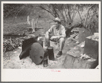 White migrant worker sitting in front of fire. He lived with two other white men migrant workers. He was a Texan. Harlingen, Texas