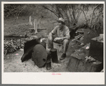 White migrant worker sitting in front of fire. He lived with two other white men migrant workers. He was a Texan. Harlingen, Texas