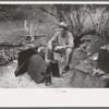 White migrant worker sitting in front of fire. He lived with two other white men migrant workers. He was a Texan. Harlingen, Texas