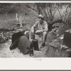 White migrant worker sitting in front of fire. He lived with two other white men migrant workers. He was a Texan. Harlingen, Texas