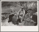 White migrant worker sitting in front of fire. He lived with two other white men migrant workers. He was a Texan. Harlingen, Texas