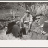 White migrant worker sitting in front of fire. He lived with two other white men migrant workers. He was a Texan. Harlingen, Texas