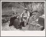 White migrant worker sitting in front of fire. He lived with two other white men migrant workers. He was a Texan. Harlingen, Texas