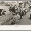 Men sitting along railroad platform waiting for work as day laborers, Raymondville, Texas