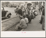 Men sitting along railroad platform waiting for work as day laborers, Raymondville, Texas