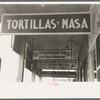 Signs hanging from balcony over sidewalk in Mexican district, Corpus Christi, Texas