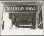 Signs hanging from balcony over sidewalk in Mexican district, Corpus Christi, Texas