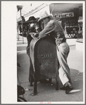 Men leaning on mailbox, Crystal City, Texas