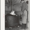 Blacksmith heating iron in forge, Southern Paper Mill construction shed, Lufkin, Texas