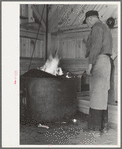 Blacksmith heating iron in forge, Southern Paper Mill construction shed, Lufkin, Texas