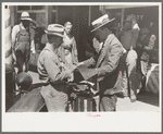 Salesman displaying sample of suit material to farmer, Hammond, Louisiana