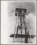 Top of derrick showing gin pole, crow's nest, crown block, traveling block, elevator and cat line. Oil well, Kilgore, Texas