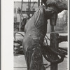 Detail of screwing one pipe into another. Oil field drilling operations, Kilgore, Texas