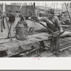 Oil field worker resting on pipe wrench, Kilgore, Texas