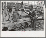 Oil field worker resting on pipe wrench, Kilgore, Texas