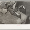 Nailing foot of boot to sole, in order to hold in place when sewing foot to welt. These nails are removed after sewing. Bootmaking shop, Alpine, Texas